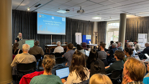 a group of people gathered in a room, listening to a presentation