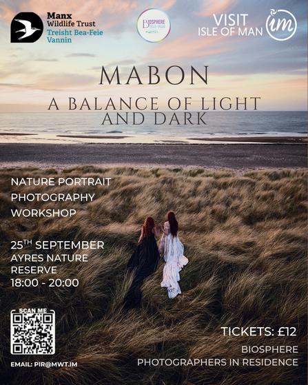 A photo of two women stood on marram grass covered sand dunes at dusk.
